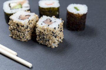 Sushi with chopsticks on black background