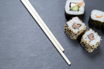 Sushi with chopsticks on black background
