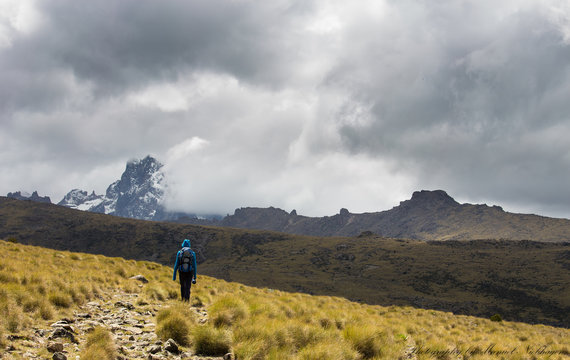 The Hiker in the Sun with Mt Kenya in dark Clouds (Kenya/ Tanzania)