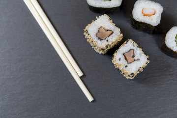 Sushi with chopsticks on black background