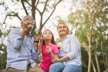 happy family in green nature park on summer ,grandfather blow soap bubbles along with grandchildren