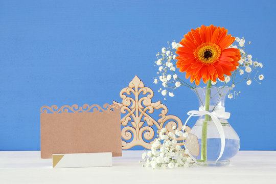fresh flowers next to empty card over wooden table