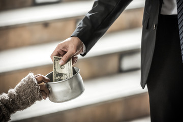 hand of kind bussiness man giving dollar money to beggar