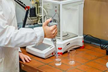Scientist is taking sample for analysis using automatic pipette dispenser 