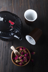 Rose buds tea on wooden bowl with tea pot