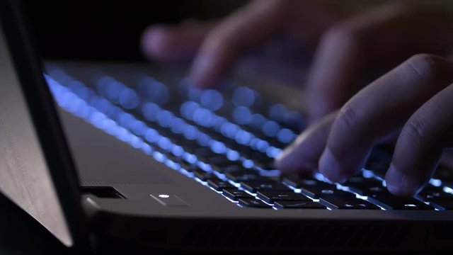 Business Woman's hand typing on laptop in the dark