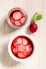 Fresh radishes cut in thin slices pickled in red wine vinegar with sugar and salt, photographed overhead with natural light (Selective Focus, Focus on the radish slices on the top)