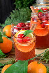 Punch with cranberries and orange decorated with mint and a stick of cinnamon in glass vessels