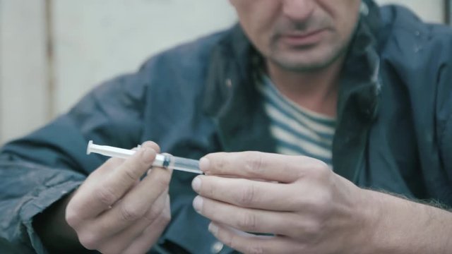 Man prepares a syringe for injection of drugs 4K