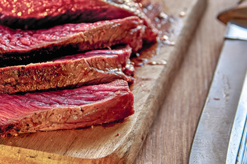 Roasted meat with blood. Well-Done Steak closeup. Half-baked barbecue. Wooden background. Selective focus.