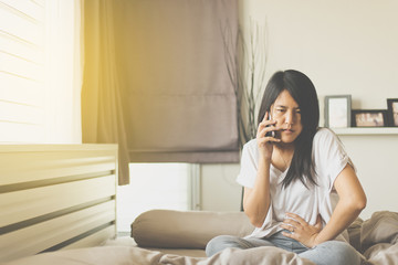 Asians woman having painful stomachache,Female suffering from abdominal pain while using mobile phone