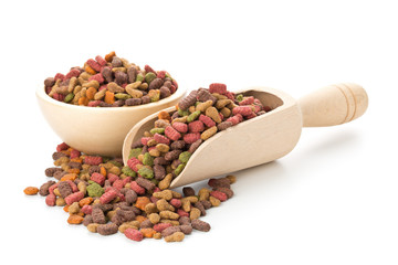 Heap of dry pet food in wooden bowl and wooden scoop
