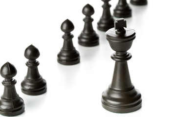 King chess figure in front of row of pawn chess figures