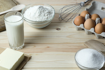 Ingredients for baking from dough. Flour, raw eggs, milk, butter, sugar on the kitchen table.