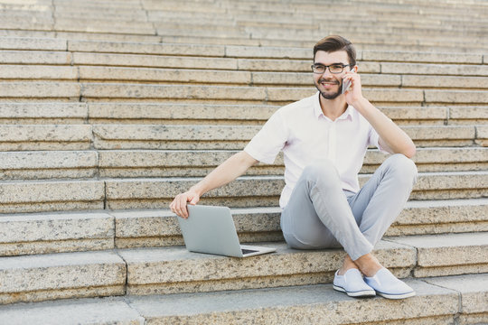 Young businessman working with laptop outdoors
