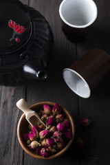 Obraz na płótnie Canvas Rose buds tea on wooden bowl with tea pot