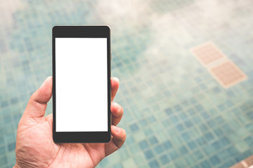 Hand holding black mobile smart phone with blank black screen over swimming pool. technology and lifestyle concept.