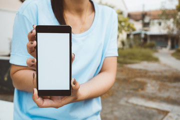 Hand holding black mobile smart phone with blank white screen at outdoor to checking e-mail or social network. technology and lifestyle concept.