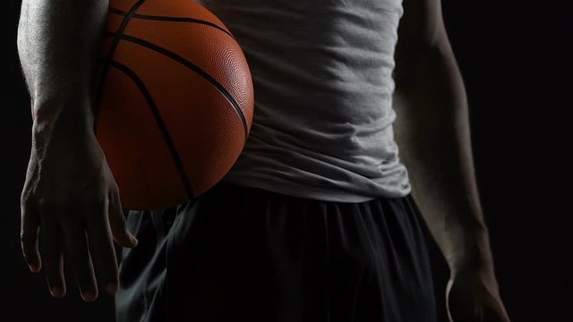Experienced basketball player standing with ball in hands, motivated strong man