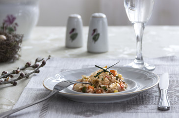 on the table napkin with a plate vegetable stew green onion glass fork knife and willow branches salt pepper sauce 