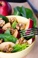 Spinach salad with nuts and apples served on table