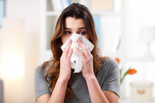 Pretty Woman Sneezing On Tissue On Couch In The Living-room