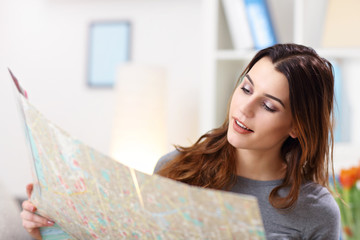 Happy woman with map at home planning holidays