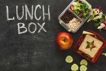 Lunch boxes filled with healthy food on black board