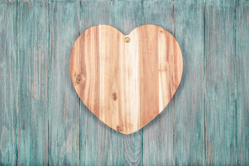 Valentine handmade wooden love heart shape hanging on vintage mint green grunge textured planks wall background. Retro old style filtered photo