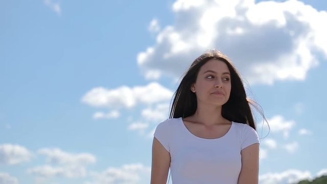 Outdoors portrait beautiful young brunette girl white t-shirt clean blue sky background summer sunny day rest relaxing leisure laughing wpman smile looking camera youthful freedom calm silence happy