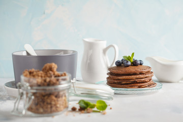 Obraz na płótnie Canvas Chocolate pancakes, chocolate baked granola in a glass jar and milk. Healthy breakfast concept.
