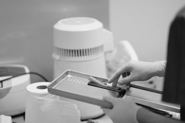 In the hands of an assistant dentist.  stainless steel pallet with tools for sterilization