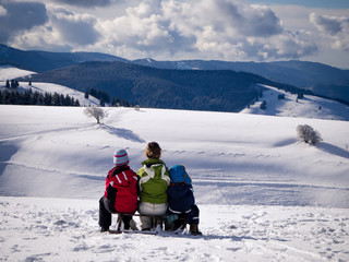 Three kids sitting on a sledge looking down the Rhine valley from a place called 