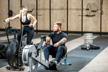Young couple training on the exercise air bicycle and rowing machine in the gym © rh2010