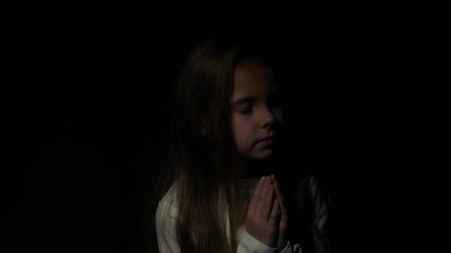 The child prays in a dark