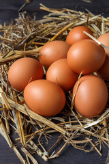 Eggs of brown chicken on a wooden background with straw with copy space in rustic vintage style