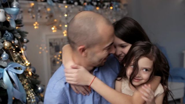Father hugging daughter near Christmas tree