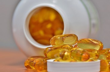 White bottle omega 3 fish oil capsules spilled lid health supplements.