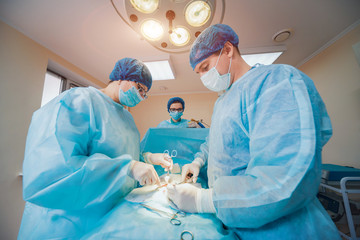 Group of surgeons in operating room with surgery equipment.