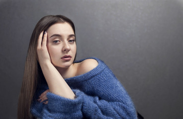 a beautiful girl in knitted blue jumper looks up