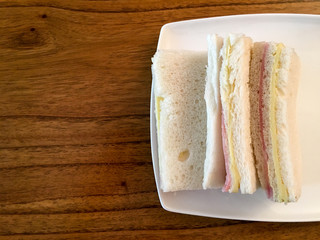 Jam and Cheese sandwich typical from Argentina in white plate over wooden table with copy space. Sandwich de miga 