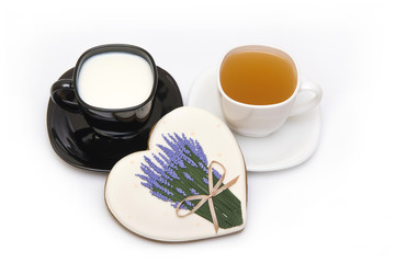 Valentine's Day still life. Black cup with milk, white cup with tea and heart-shaped cake.