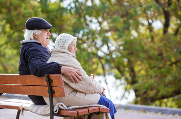 Senior couple sitting on bench in autumn park