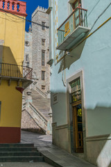 Colorful buildings with architectural lines and details, with a peek-a-boo view of the University of Guanajuato steps and building, in Guanajuato, Mexico - 190929746