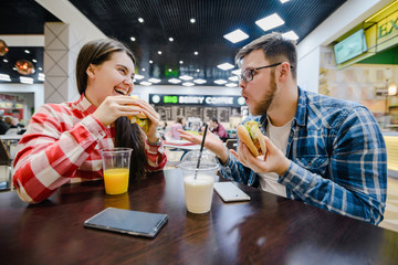 couple make pause for shopping eat burgers in mall cafe