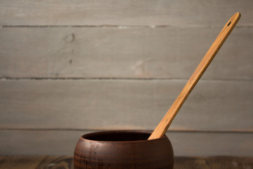 clay pot with a wooden spoon on a wooden background