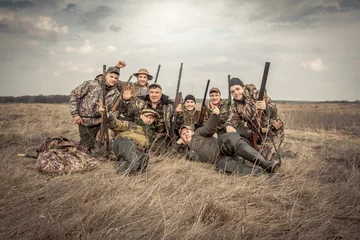 Foto auf Acrylglas Men hunters group team portrait in rural field posing together against overcast sky during hunting season. Concept for teamwork © splendens