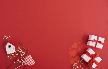 Tiny toy house, valentines heart key, gift boxes and white flowers over red background, Valentines day card