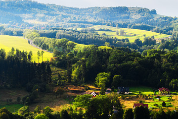 Hills and sunny valley in the Walbrzyskie Mountains (Gory Walbrzyskie) or Waldenburg Mountains. Vast panorama of picturesque countryside landscape in Sudetes, Poland. Aerial view.