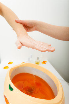 Woman getting paraffin hand treatment at beautician